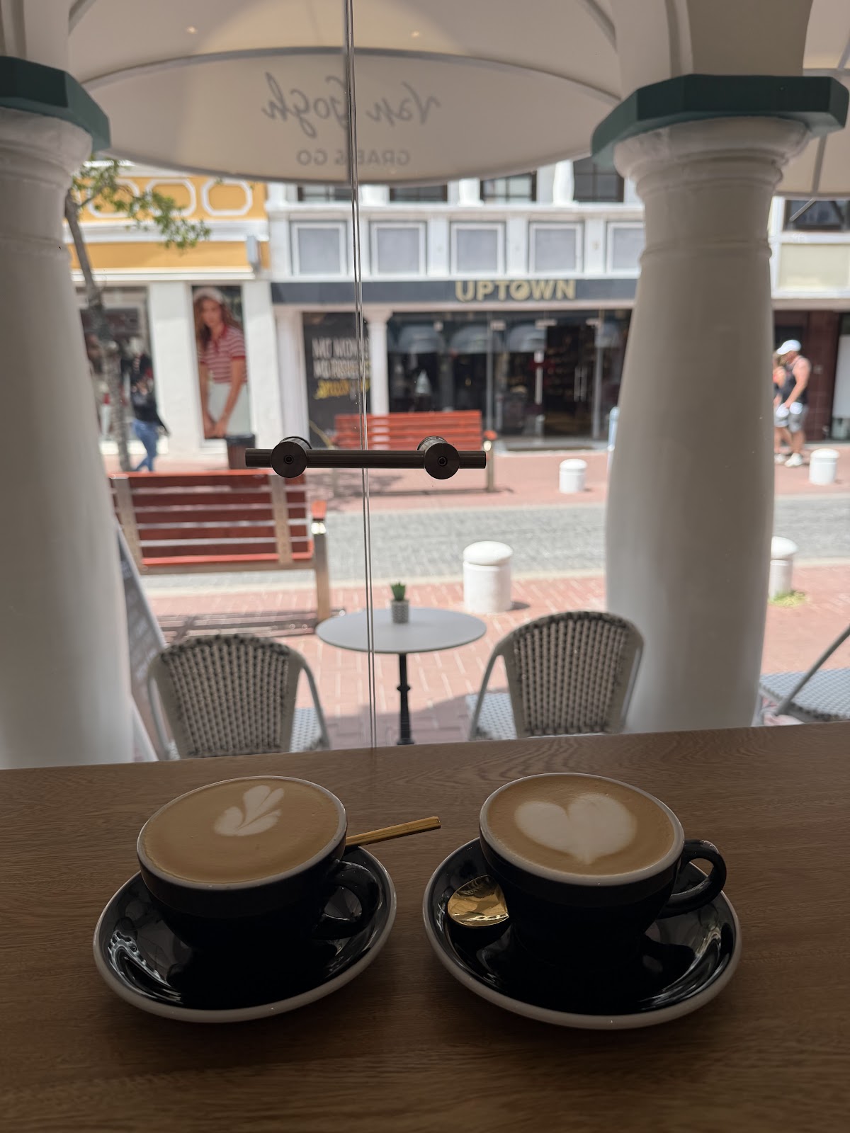 Two flat whites with latte art on the window bar of Van Gogh Grab & Go, looking onto Breedestraat