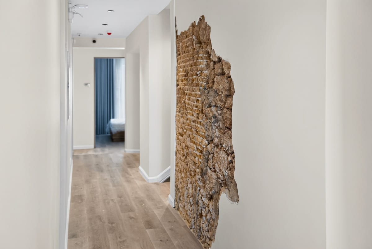 A corridor on the second floor of Majestic City Palace with a tall panel of original 1892 coral stone left exposed in the lime washed wall