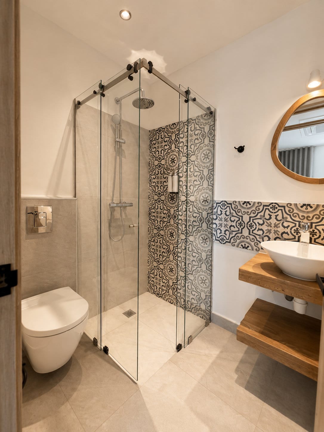 A city view room bathroom with a corner rain shower behind glass, a wall of majolica, a wall hung lavatory and a vessel basin on an oak shelf