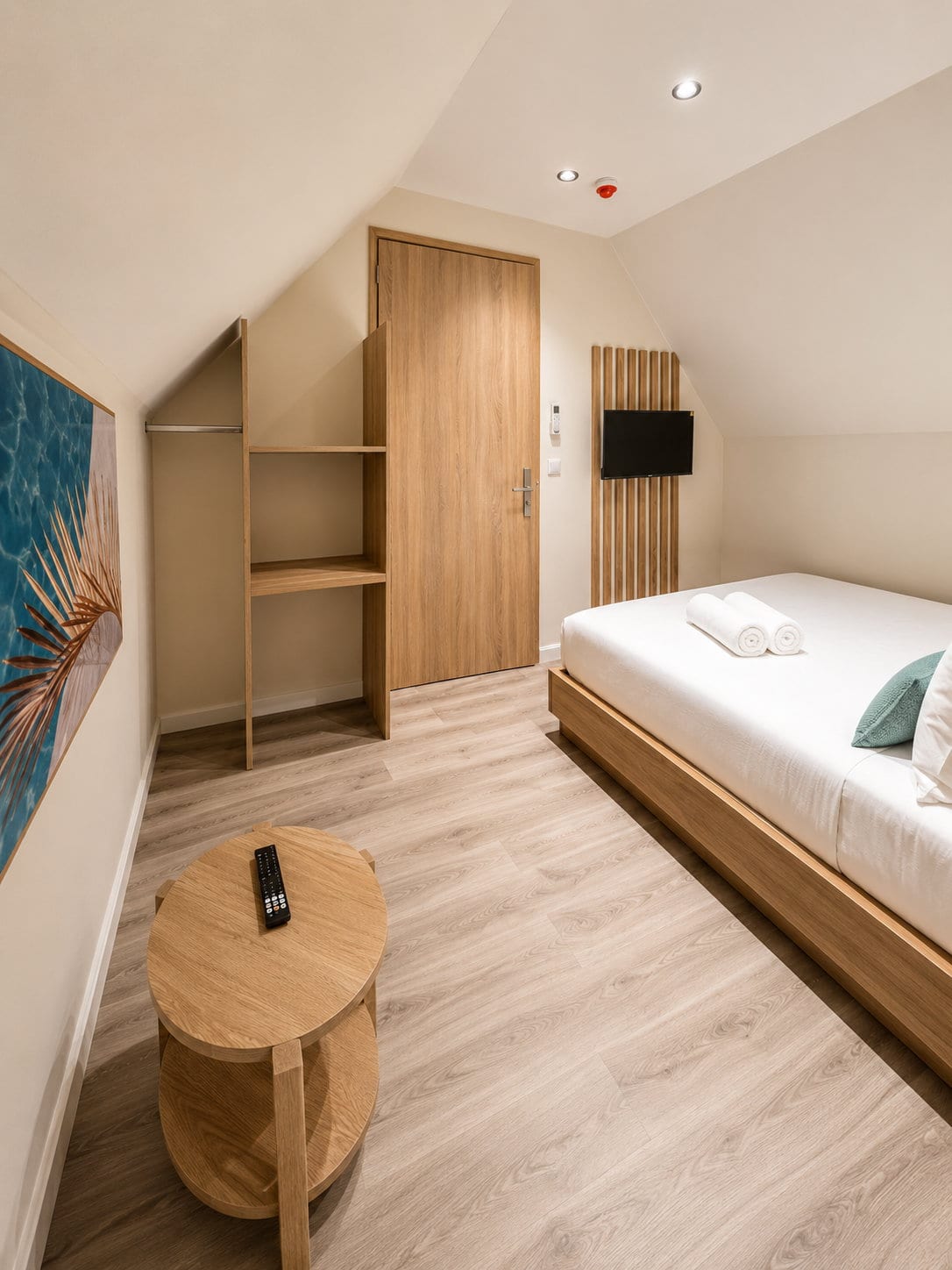 Built in oak shelving and hanging space beside the door, with a round oak side table on the pale floor