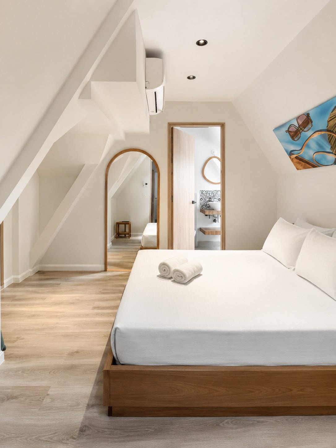 The loft from the foot of the bed: the stair soffit, a full height arched mirror and the tiled bathroom through the open door