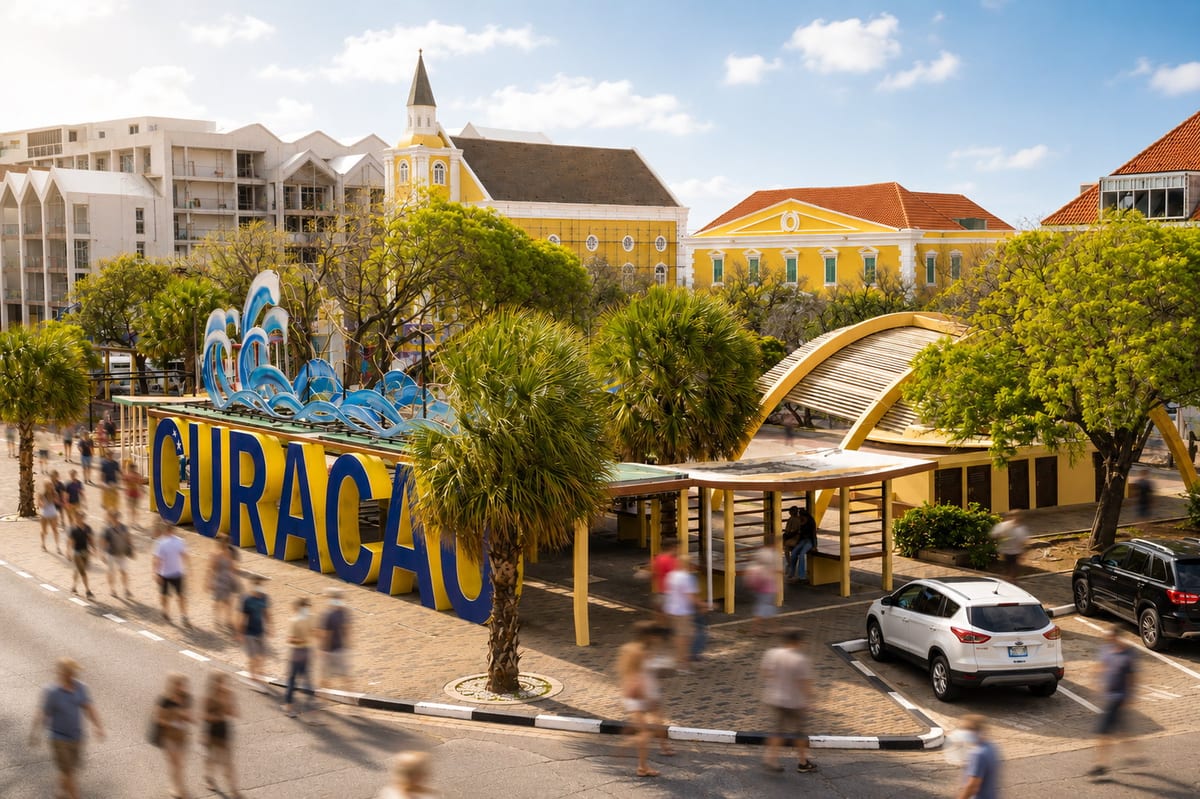 The blue and yellow Curaçao letters on the Punda waterfront in Willemstad, with pastel Dutch colonial gables and a church tower behind