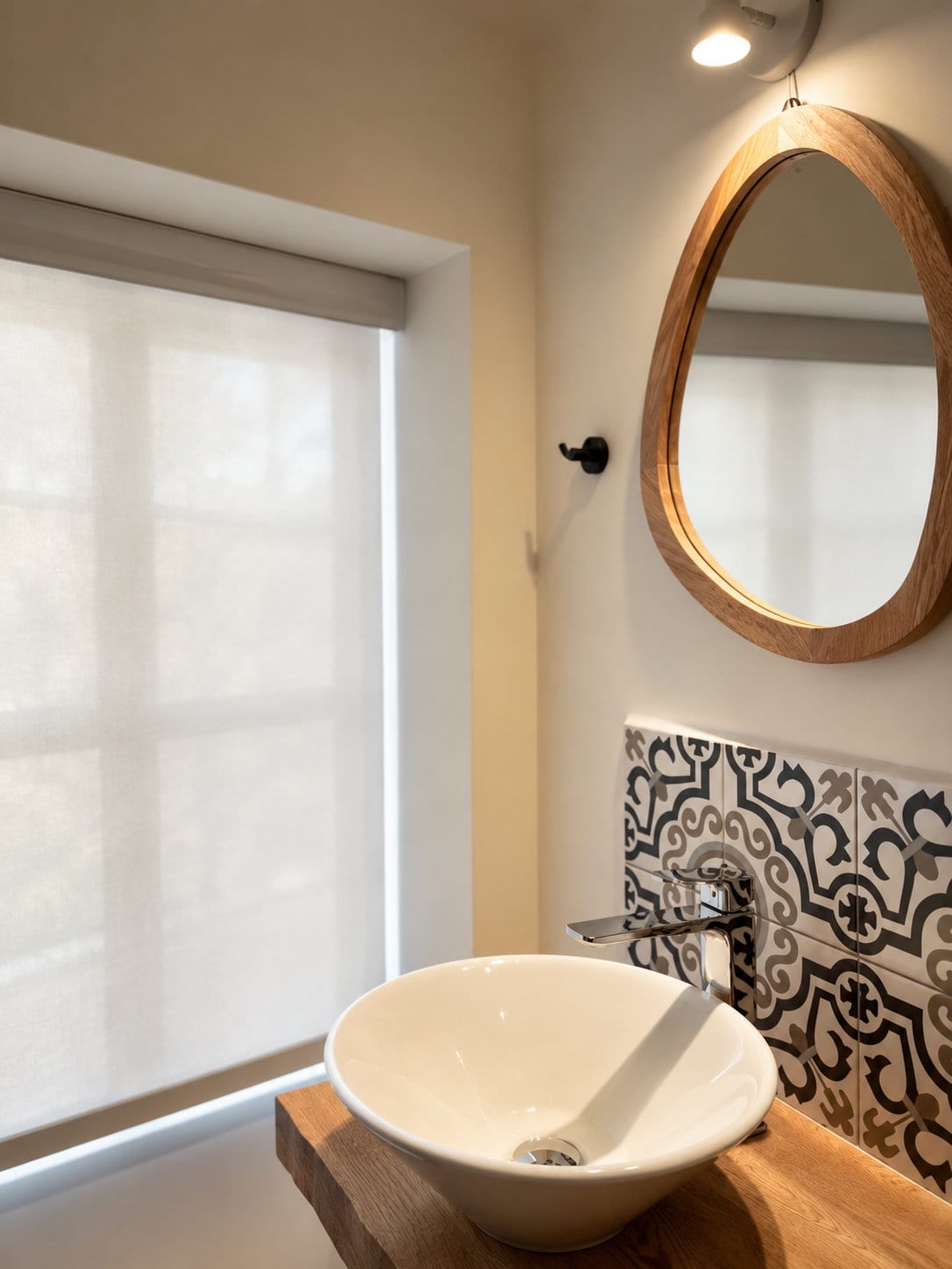 A vessel basin on an oak shelf under a round mirror, with blue and white majolica tile behind it, in a loft bathroom at Majestic City Palace
