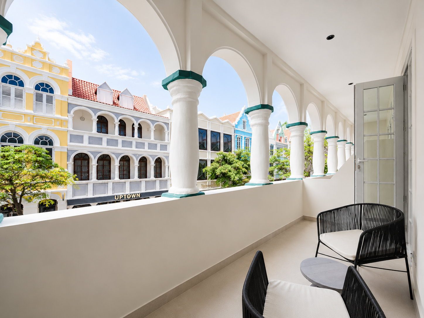 The private balcony of a Signature King Room at Majestic City Palace, overlooking the painted Handelskade merchant houses and the harbour of Punda, Willemstad