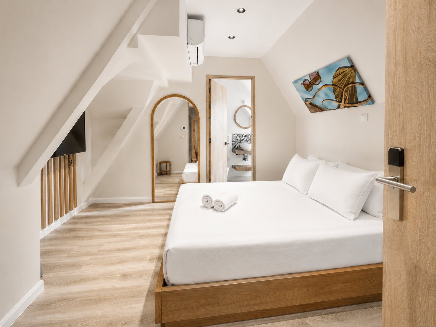 A top-floor Signature Cozy Loft at Majestic City Palace with sloping ceilings, a made bed and warm oak floors
