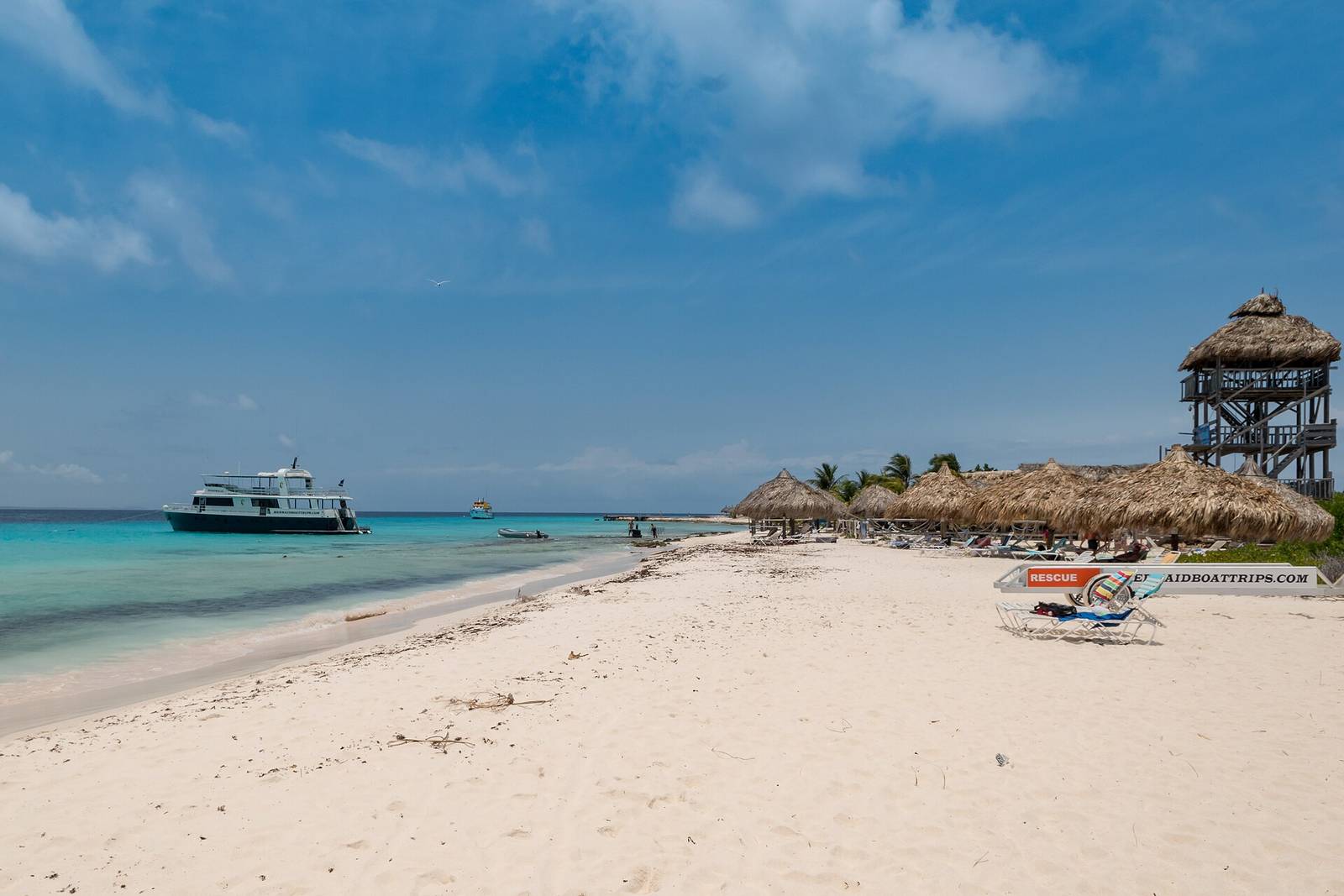 The long white beach of Klein Curaçao with a boat anchored in clear turquoise water