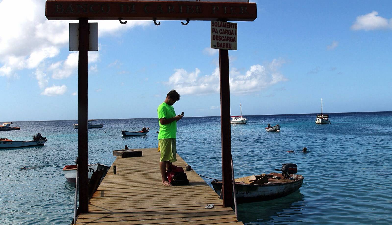 The fishing pier and clear turquoise shallows at Playa Piskado near Westpunt