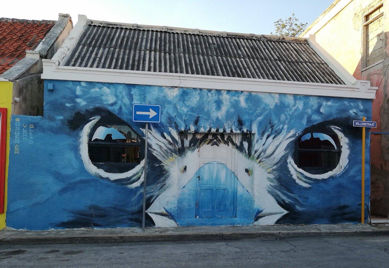 A vivid mural painted across a building wall in a Willemstad alley
